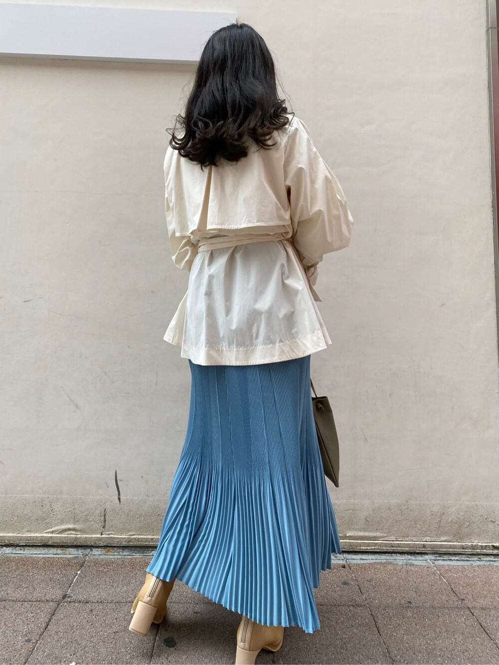 ブルー系のスカート、ベージュ系のブーツ、ホワイト系のニット/セーターを着用したレディースの春コーディネートの5枚目の写真