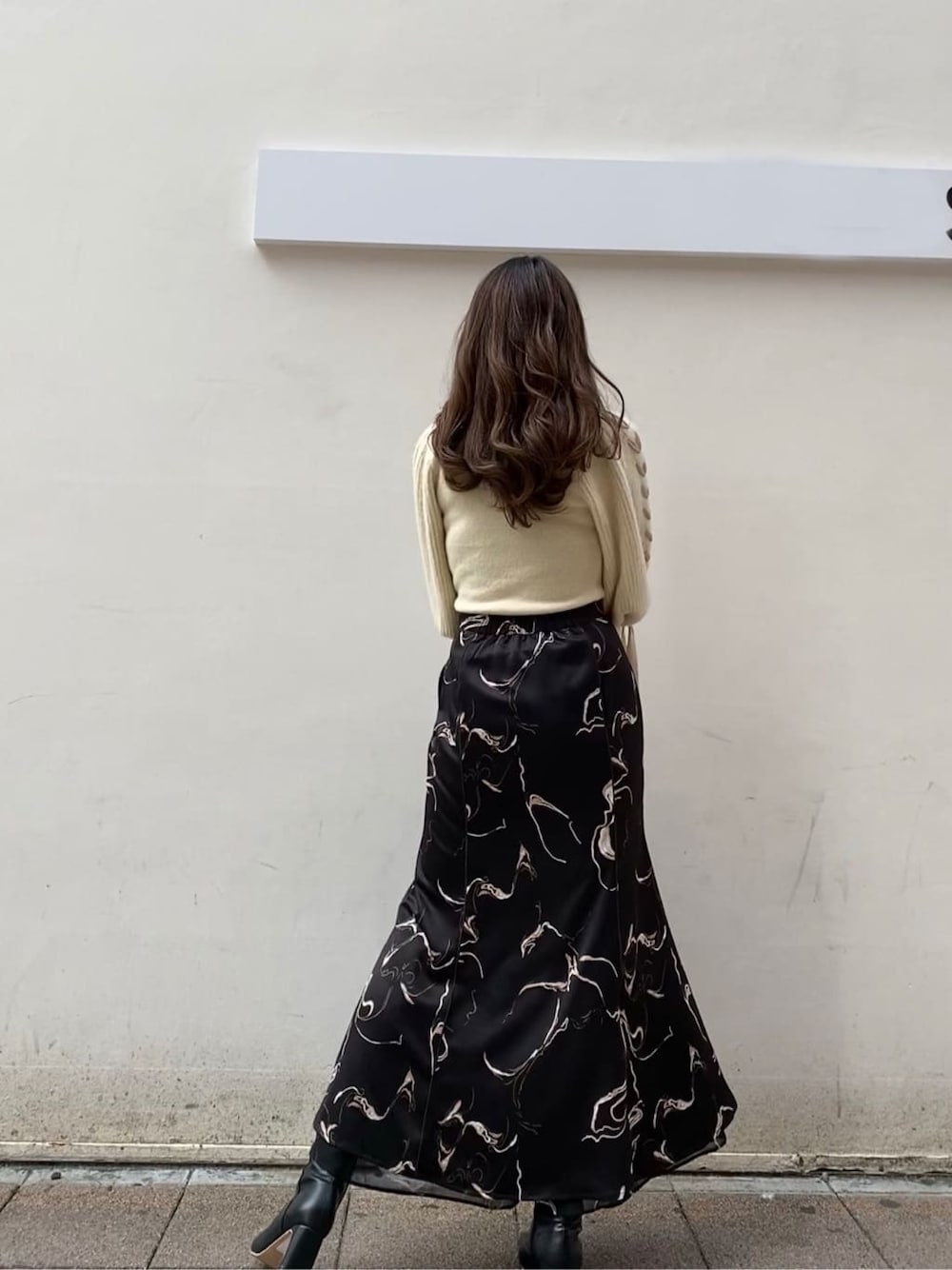 ブラック系のスカート、ホワイト系のニット/セーターを着用したレディースの秋コーディネートの5枚目の写真