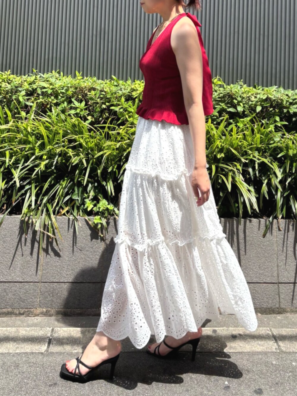 ブラック系のサンダル、レッド系のニット/セーター、ホワイト系のスカートを着用したレディースの夏コーディネートの3枚目の写真