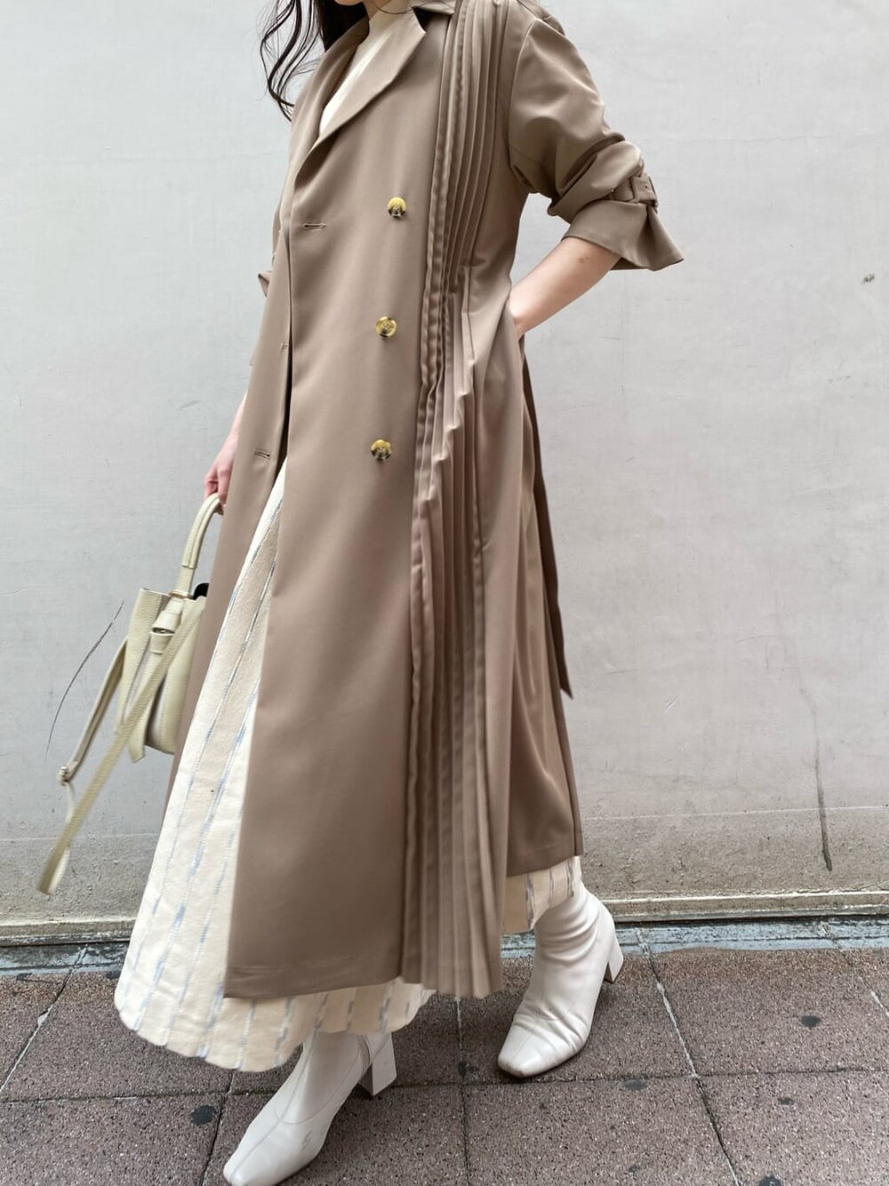 ベージュ系のトレンチコート、ホワイト系のワンピース、ホワイト系のハンドバッグを着用したレディースの春コーディネートの6枚目の写真