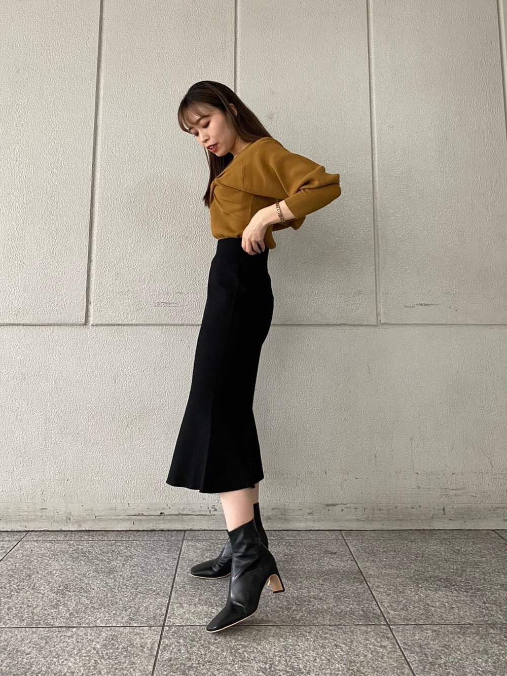 ブラック系のその他シューズ、ブラック系のスカート、イエロー系のニット/セーターを着用したレディースの秋コーディネートの4枚目の写真