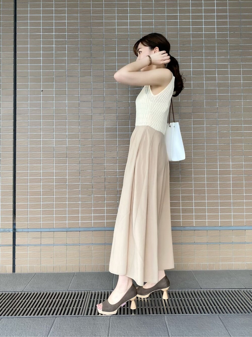 ブラウン系のパンプス、ホワイト系のハンドバッグ、ホワイト系のワンピースを着用したレディースの夏コーディネートの4枚目の写真