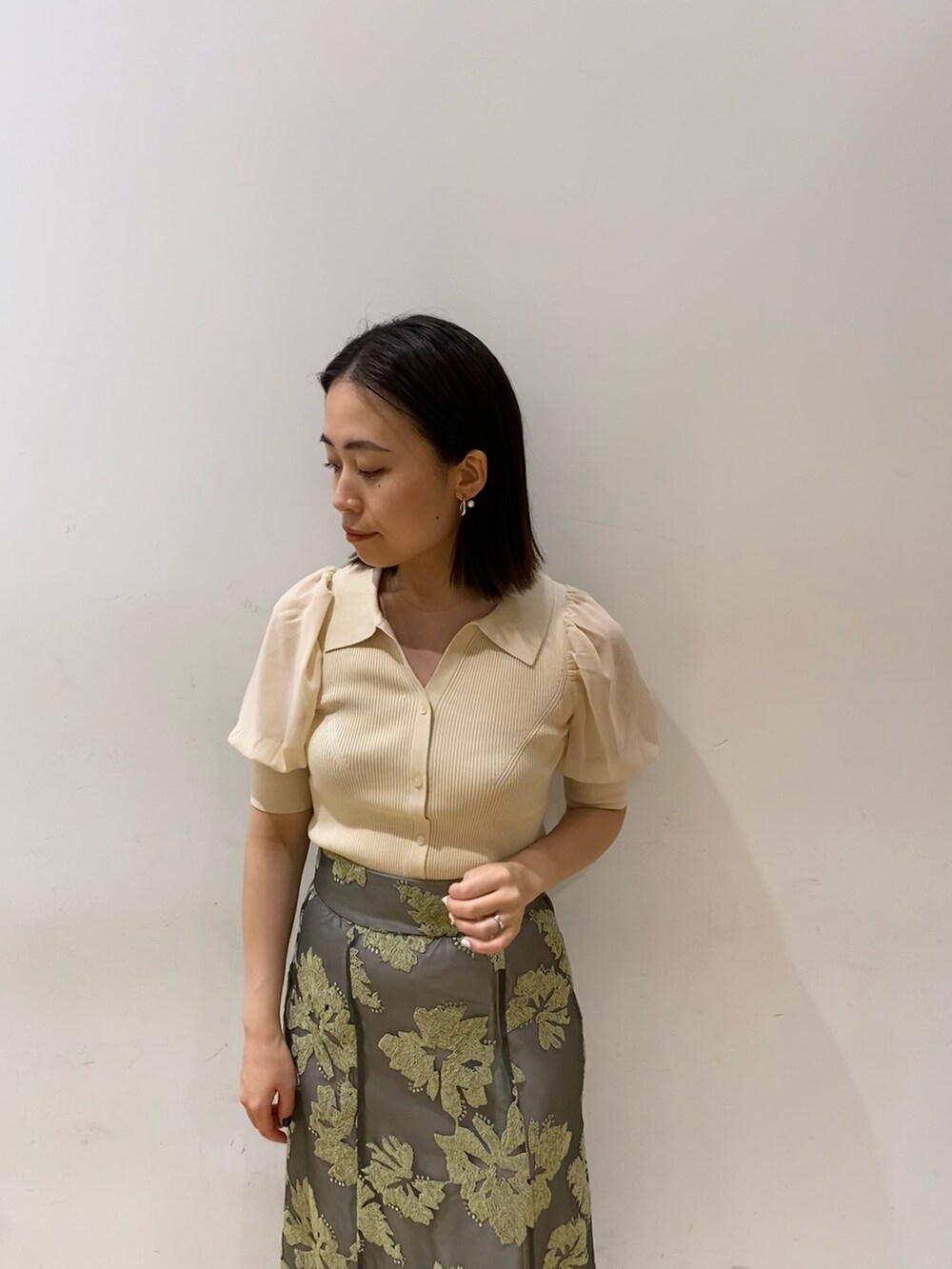 グリーン系のスカート、ホワイト系のニット/セーターを着用したレディースの夏コーディネートの2枚目の写真