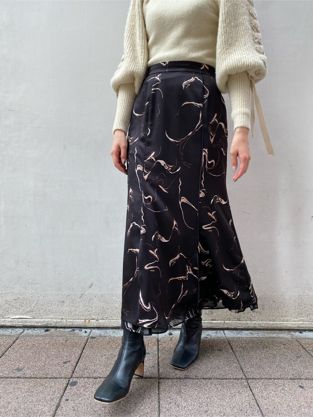 ブラック系のスカート、ホワイト系のニット/セーターを着用したレディースの秋コーディネートの3枚目の写真