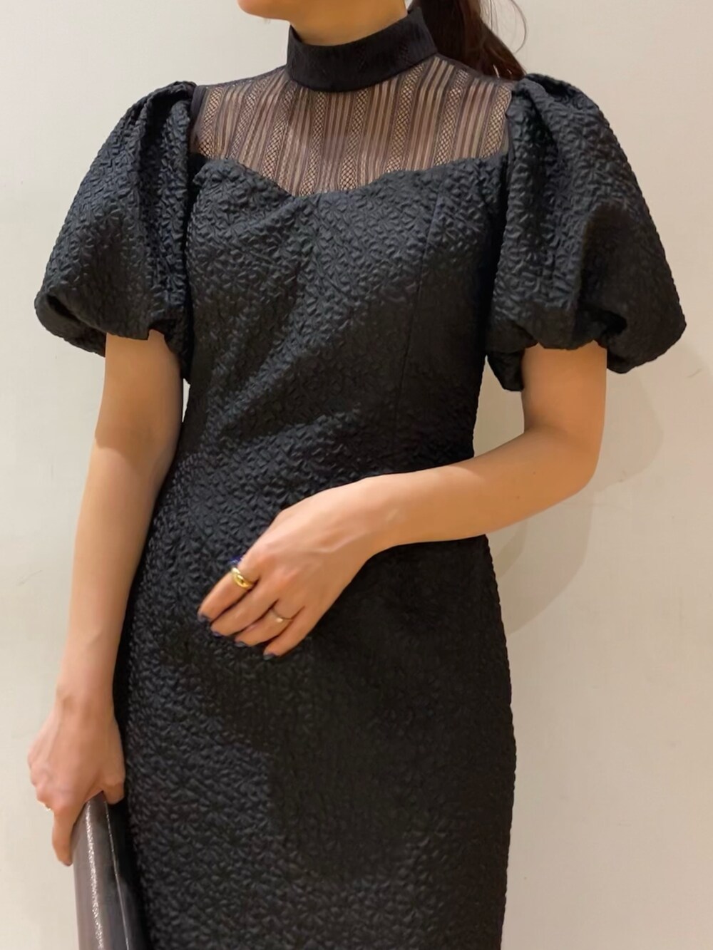 ブラック系のドレス、シルバー系のクラッチバッグ、シルバー系のパンプスを着用したレディースの秋コーディネートの5枚目の写真