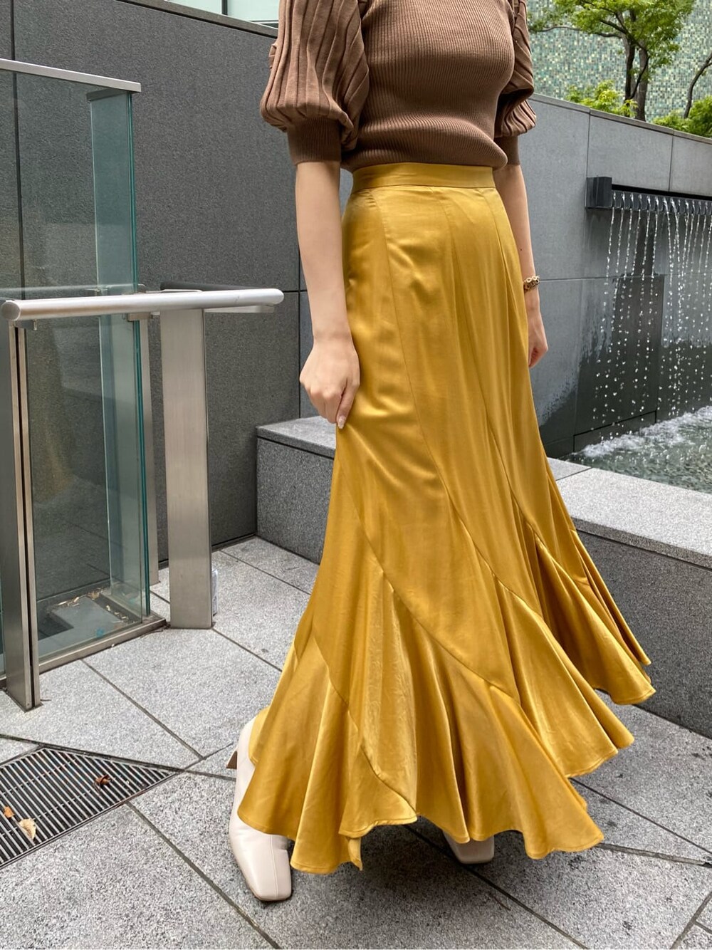 イエロー系のスカート、ホワイト系のその他シューズ、ブラウン系のニット/セーターを着用したレディースの夏コーディネートの4枚目の写真