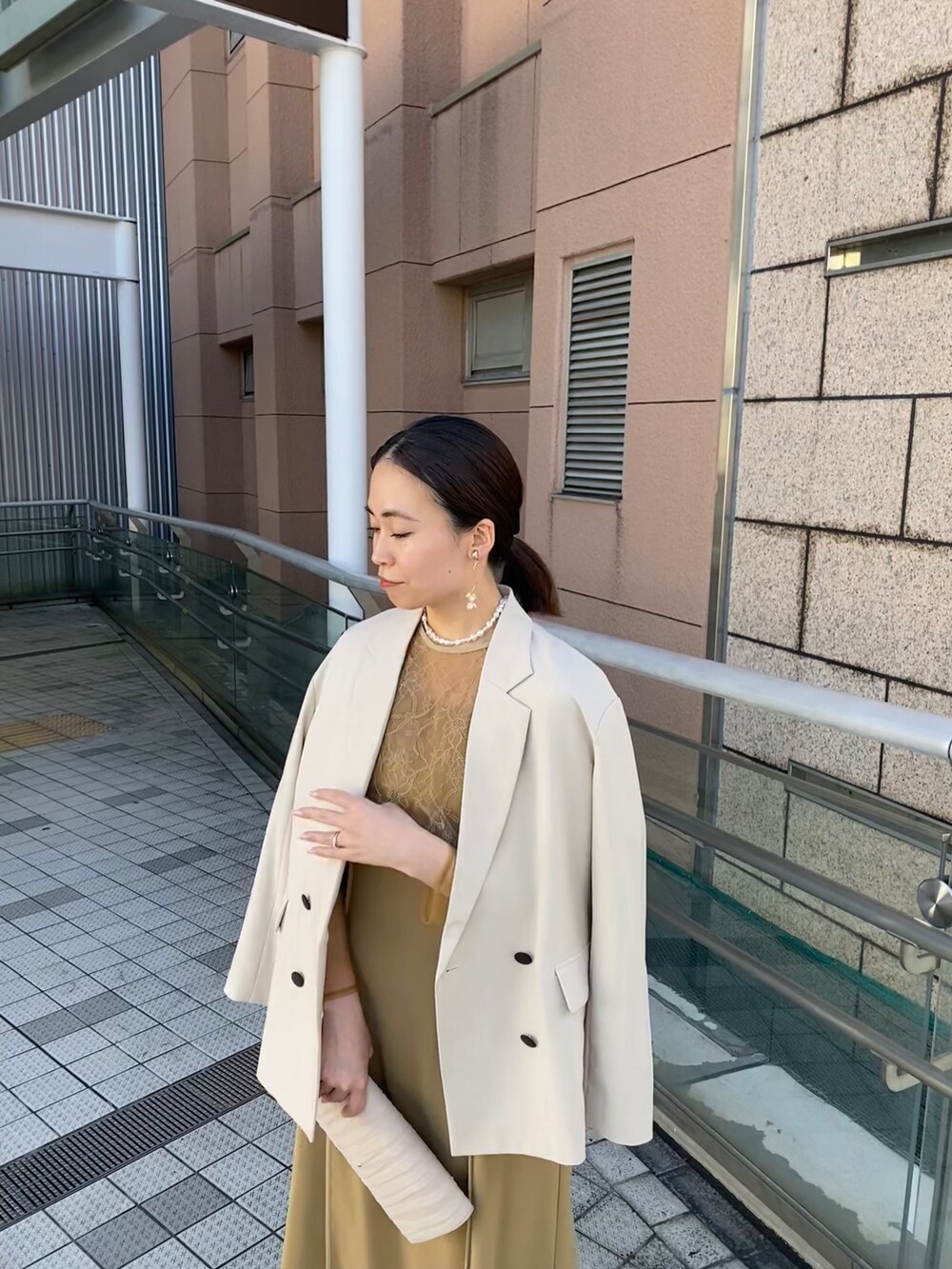 ベージュ系のドレス、ベージュ系のテーラードジャケット、ベージュ系のハンドバッグを着用したレディースの秋コーディネートの6枚目の写真