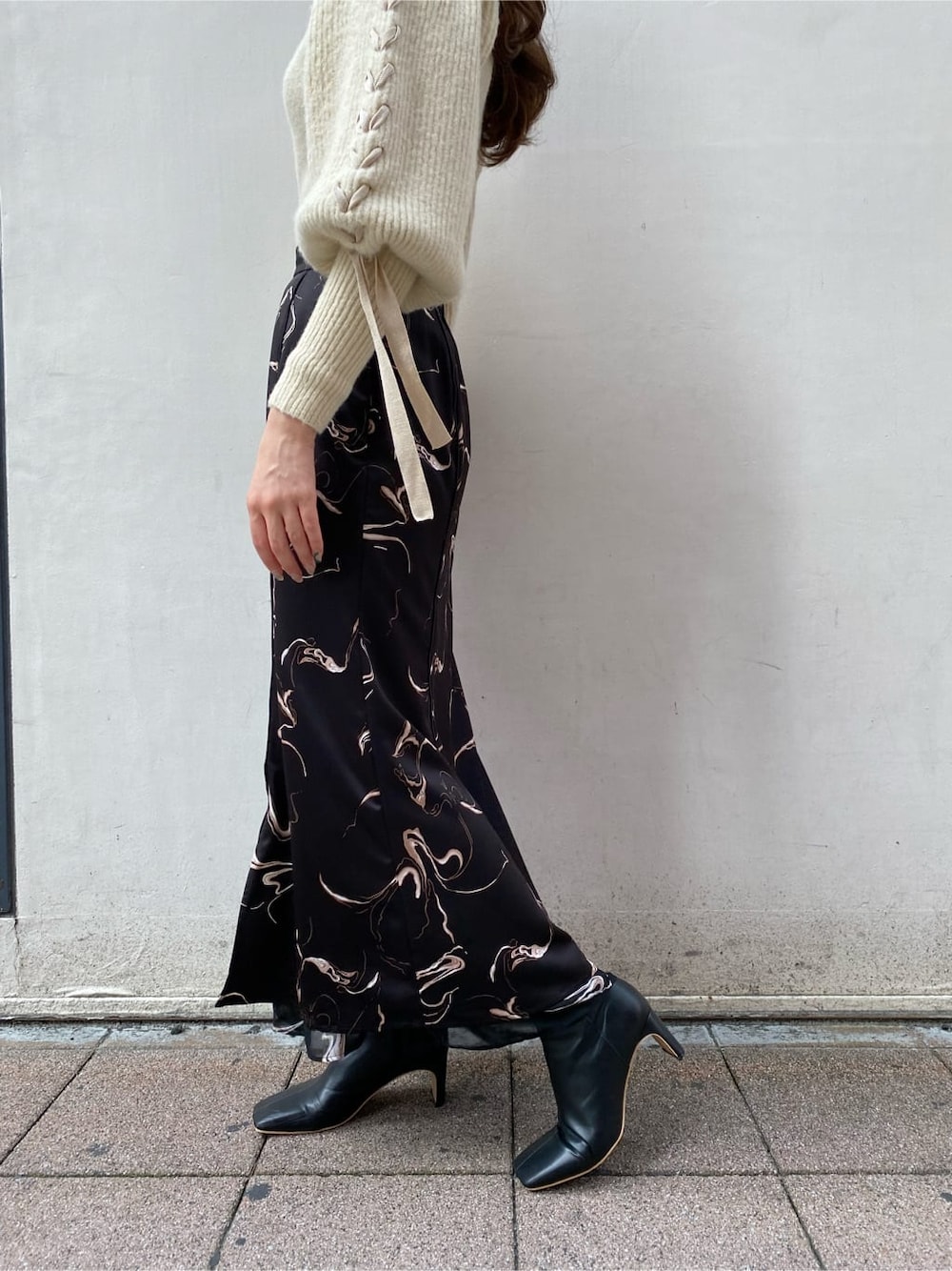 ブラック系のスカート、ホワイト系のニット/セーターを着用したレディースの秋コーディネートの2枚目の写真