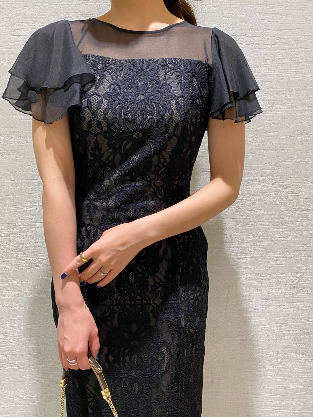 ブラック系のドレス、ゴールド系のクラッチバッグ、ゴールド系のパンプスを着用したレディースの秋コーディネートの4枚目の写真