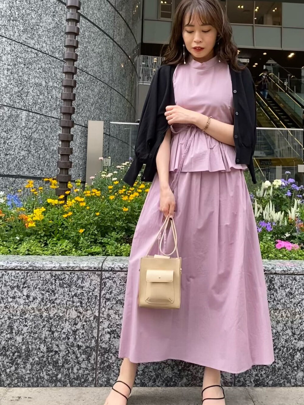 パープル系のワンピース、ブラック系のサンダル、ベージュ系のハンドバッグを着用したレディースの夏コーディネートの2枚目の写真