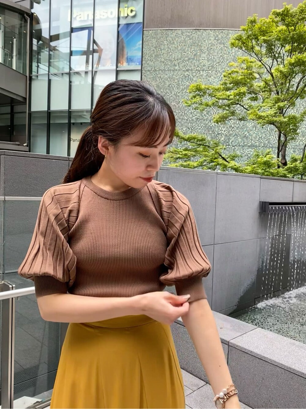 イエロー系のスカート、ホワイト系のその他シューズ、ブラウン系のニット/セーターを着用したレディースの夏コーディネートの2枚目の写真