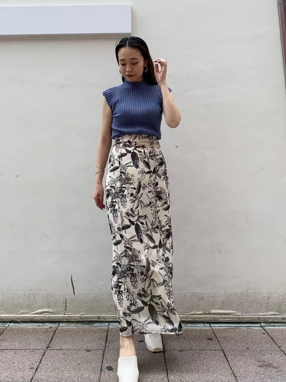 ベージュ系のスカート、ブルー系のニット/セーターを着用したレディースの夏コーディネートの2枚目の写真