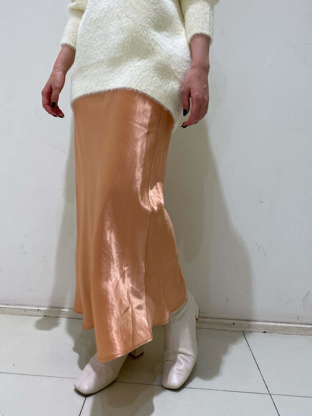 ホワイト系のニット/セーター、オレンジ系のスカートを着用したレディースの冬コーディネートの4枚目の写真