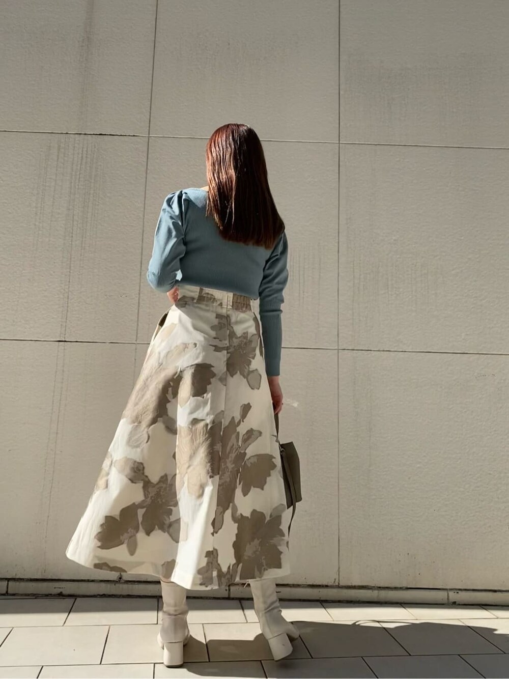 ブルー系のニット/セーター、ベージュ系のスカート、ベージュ系のハンドバッグを着用したレディースの冬コーディネートの4枚目の写真