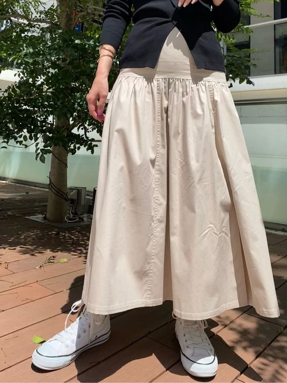 ベージュ系のスカート、ブラック系のニット/セーターを着用したレディースの秋コーディネートの2枚目の写真