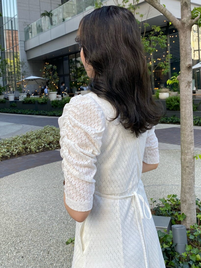 ゴールド系のハンドバッグ、ホワイト系のワンピース、ブラック系のサンダルを着用したレディースの夏コーディネートの2枚目の写真