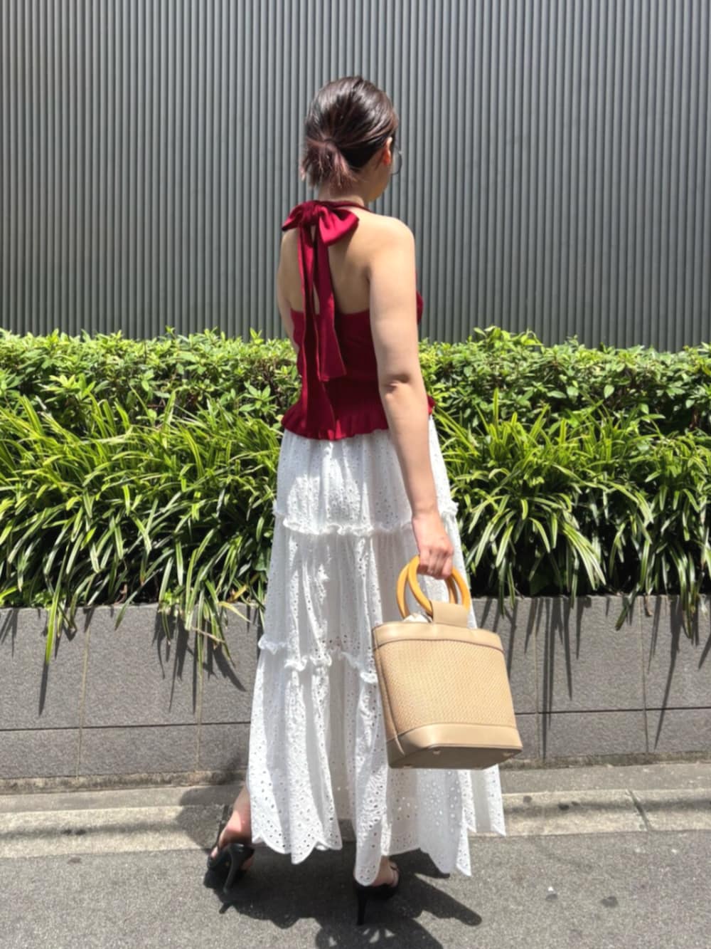 ブラック系のサンダル、レッド系のニット/セーター、ホワイト系のスカートを着用したレディースの夏コーディネートの2枚目の写真