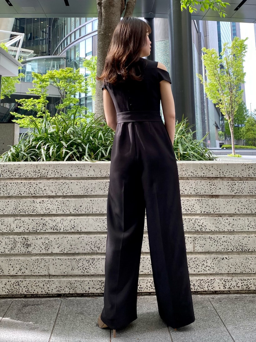 ゴールド系のハンドバッグ、ブラック系のパンツドレス、ゴールド系のパンプスを着用したレディースの春コーディネートの5枚目の写真