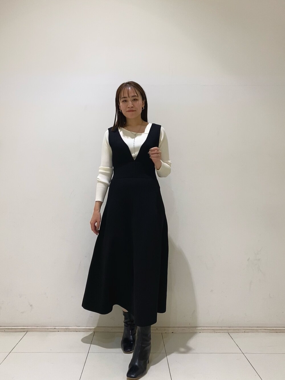 ブラック系のジャンパースカート、ホワイト系のニット/セーターを着用したレディースの秋コーディネートの2枚目の写真