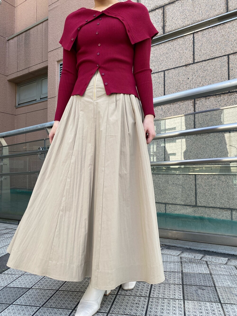 レッド系のニット/セーター、ベージュ系のスカートを着用したレディースの冬コーディネートの2枚目の写真