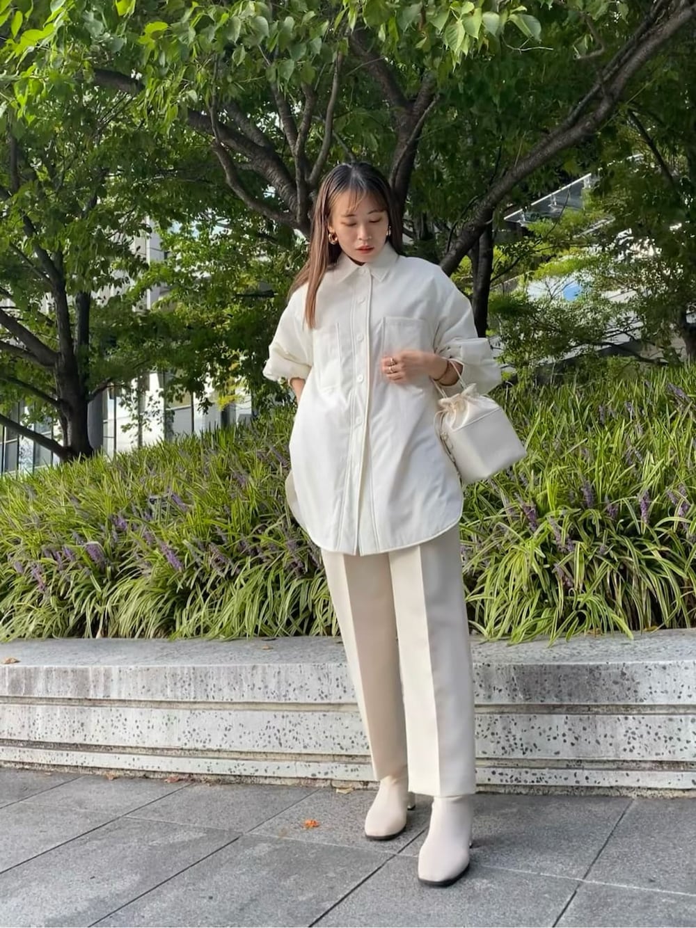 ホワイト系のステンカラーコート、ホワイト系のその他パンツ、ホワイト系のハンドバッグを着用したレディースの秋コーディネートの3枚目の写真