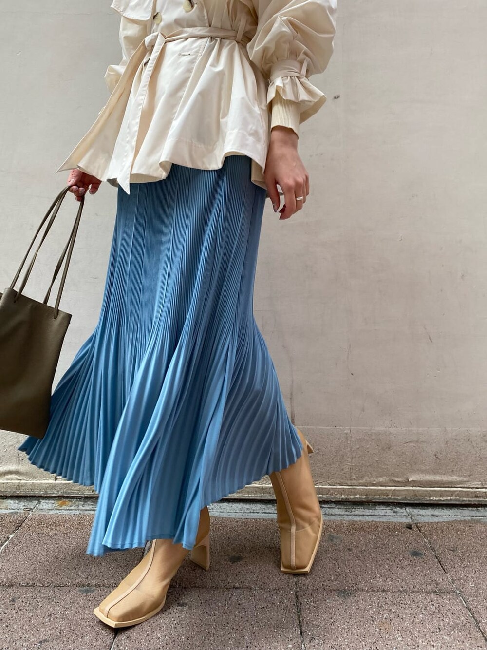 ブルー系のスカート、ベージュ系のブーツ、ホワイト系のニット/セーターを着用したレディースの春コーディネートの3枚目の写真