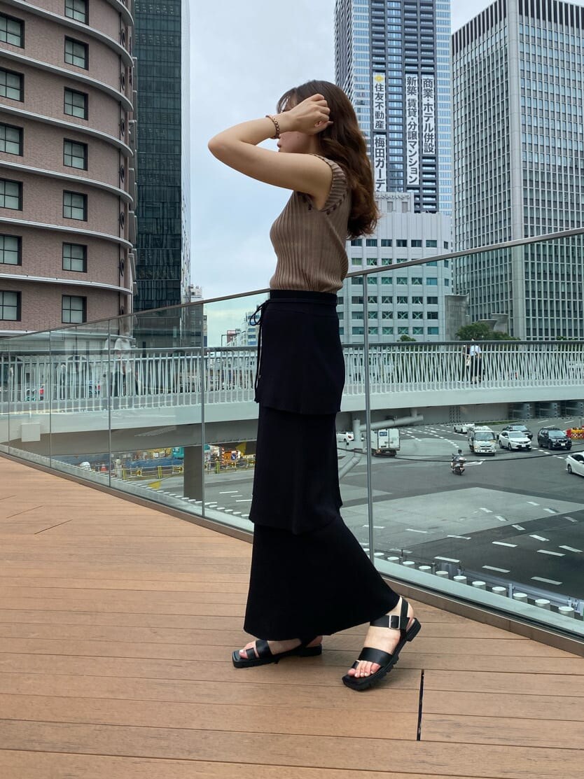 ブラック系のスカート、ブラック系のサンダル、ベージュ系のニット/セーターを着用したレディースの夏コーディネートの2枚目の写真