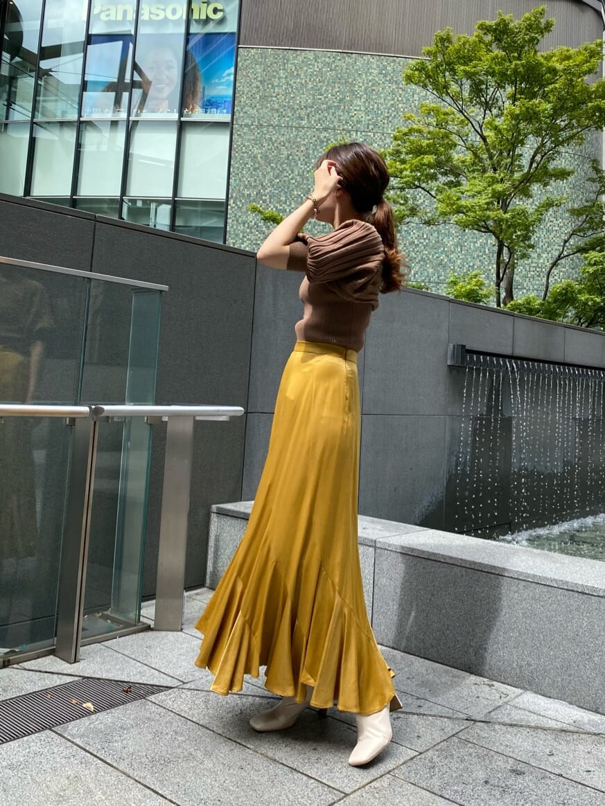 イエロー系のスカート、ホワイト系のその他シューズ、ブラウン系のニット/セーターを着用したレディースの夏コーディネートの3枚目の写真