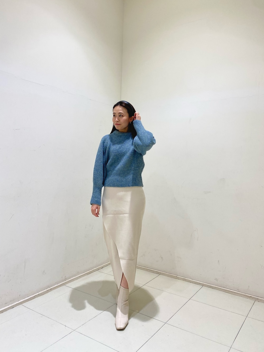 グリーン系のニット/セーター、ホワイト系のスカートを着用したレディースの冬コーディネートの2枚目の写真