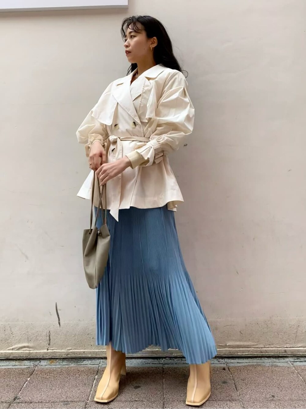 ブルー系のスカート、ベージュ系のブーツ、ホワイト系のニット/セーターを着用したレディースの春コーディネートの2枚目の写真