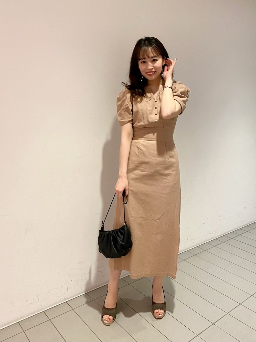 ブラウン系のパンプス、ブラック系のハンドバッグ、ベージュ系のワンピースを着用したレディースの春コーディネートの2枚目の写真