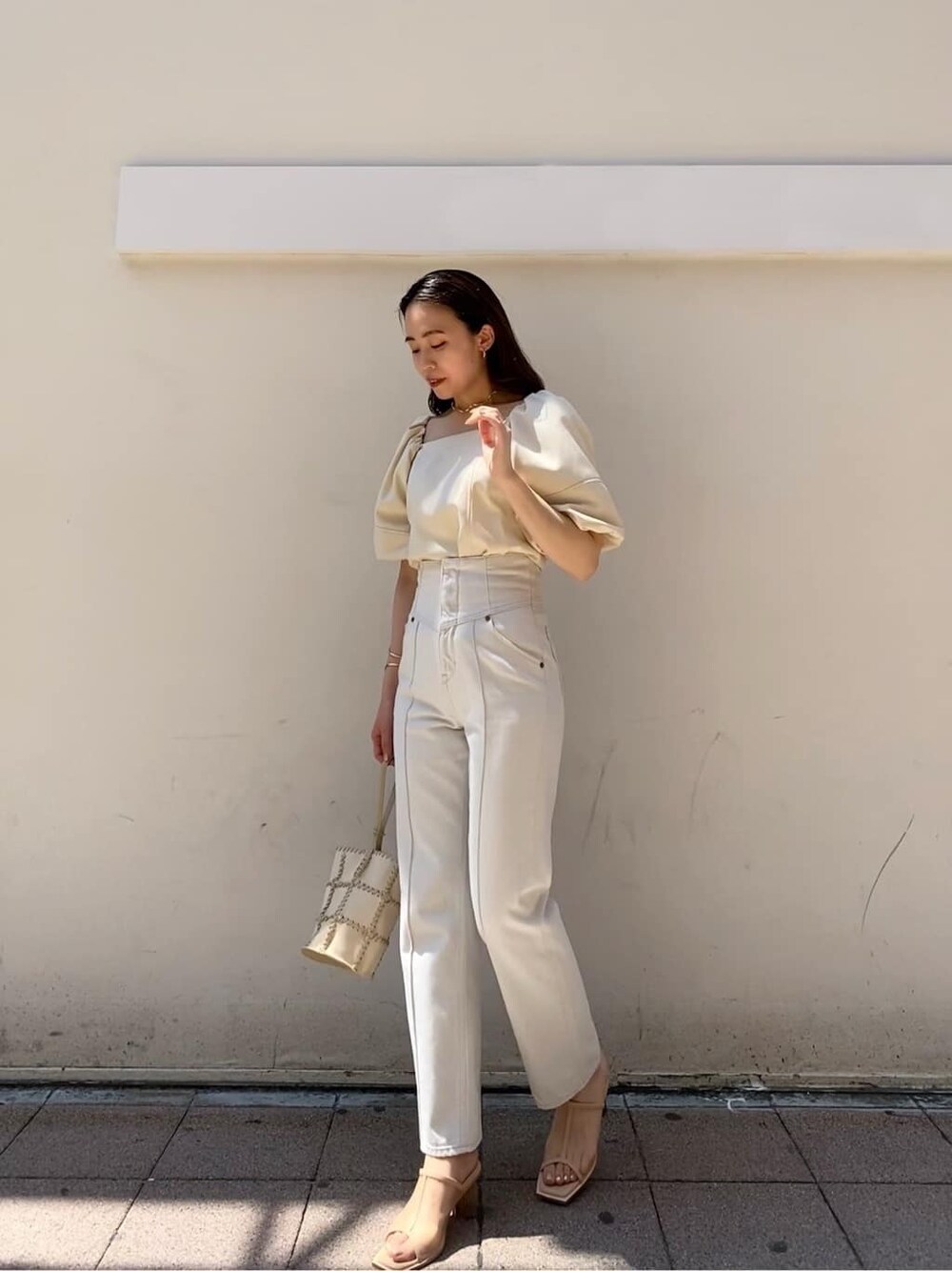 ホワイト系のデニムパンツ、ホワイト系のショルダーバッグ、ベージュ系のサンダルを着用したレディースの夏コーディネートの2枚目の写真