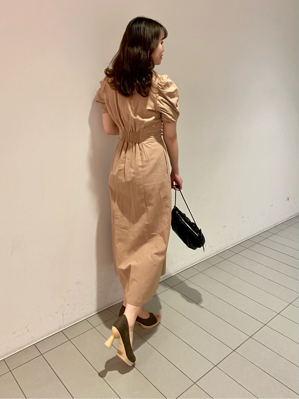 ブラウン系のパンプス、ブラック系のハンドバッグ、ベージュ系のワンピースを着用したレディースの春コーディネートの4枚目の写真