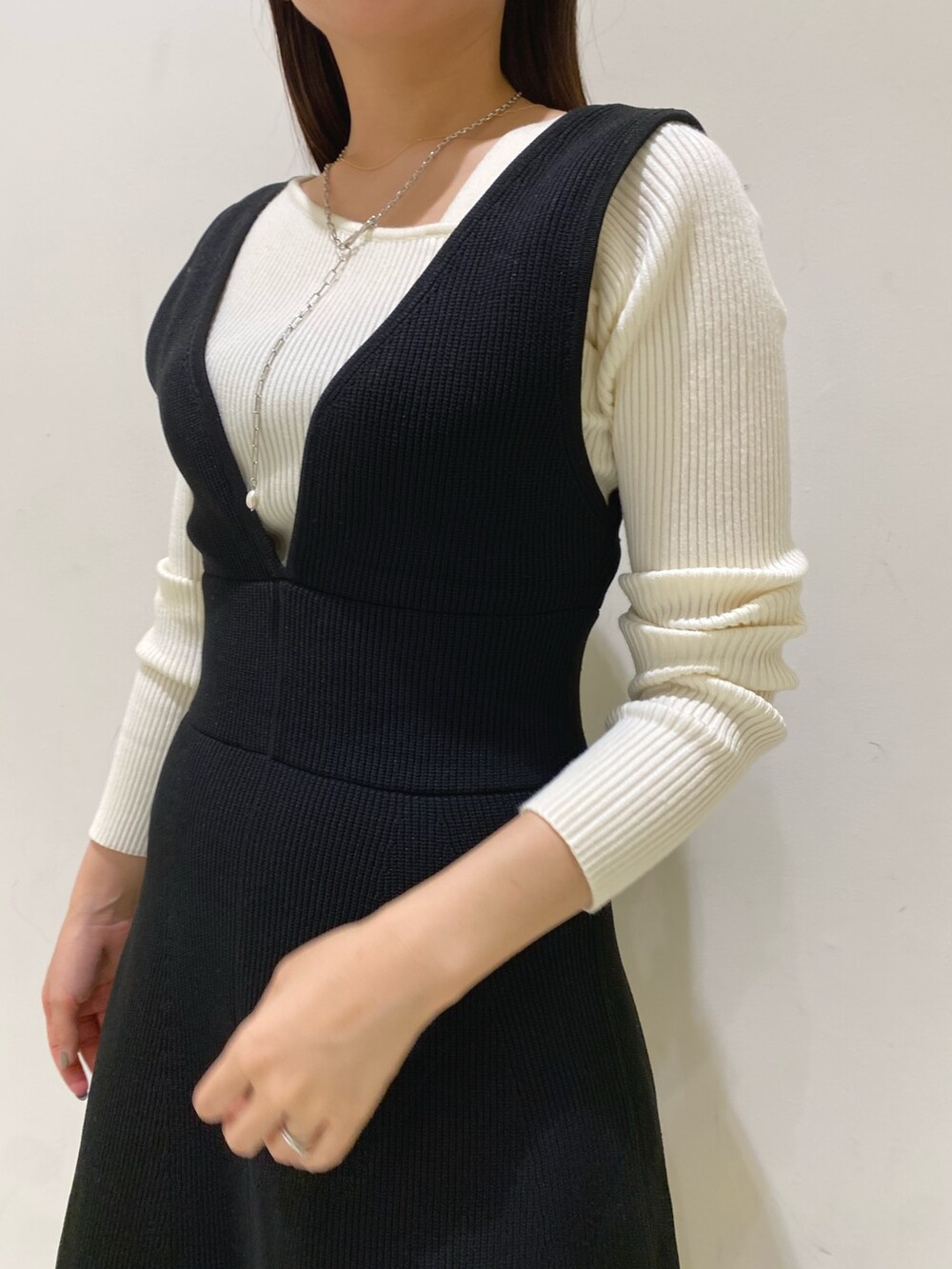 ブラック系のジャンパースカート、ホワイト系のニット/セーターを着用したレディースの秋コーディネートの4枚目の写真