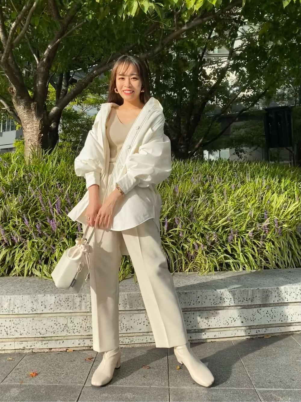 ホワイト系のステンカラーコート、ホワイト系のその他パンツ、ホワイト系のハンドバッグを着用したレディースの秋コーディネートの4枚目の写真