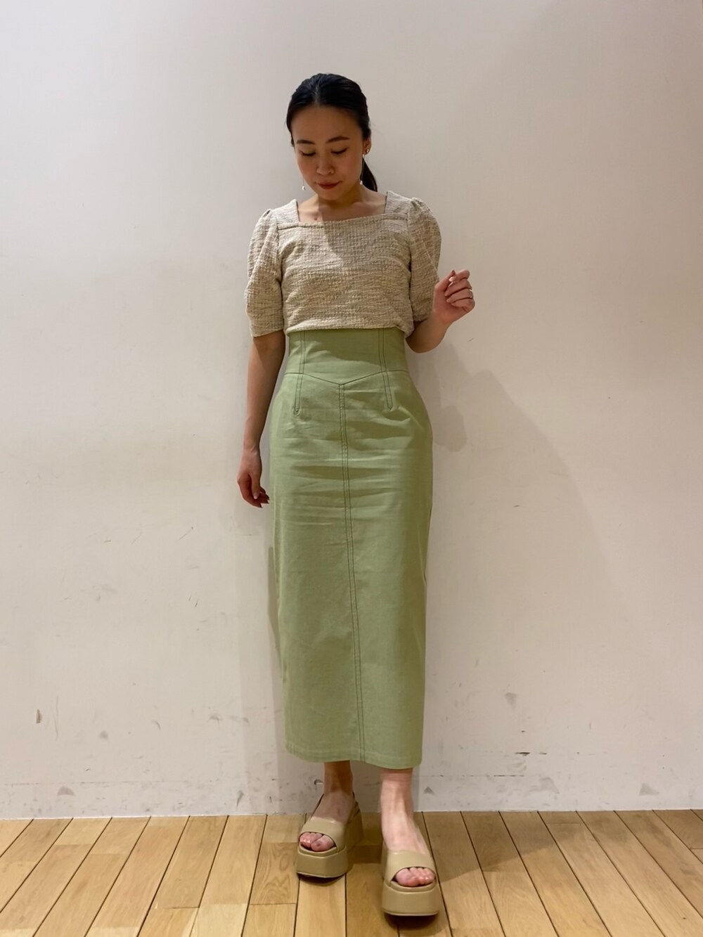 ベージュ系のTシャツ/カットソー、グリーン系のスカート、ベージュ系のサンダルを着用したレディースの春コーディネートの2枚目の写真