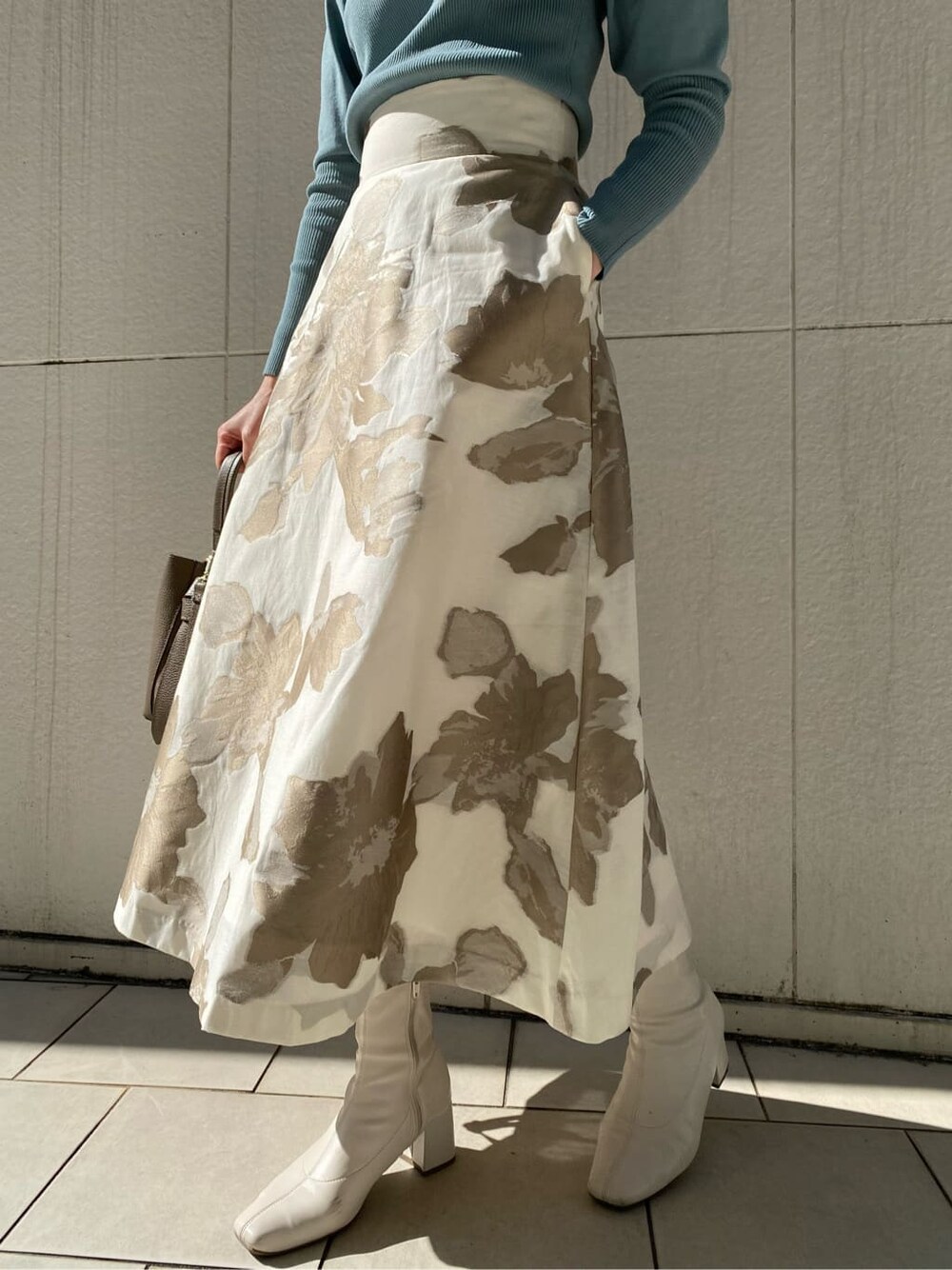 ブルー系のニット/セーター、ベージュ系のスカート、ベージュ系のハンドバッグを着用したレディースの冬コーディネートの2枚目の写真