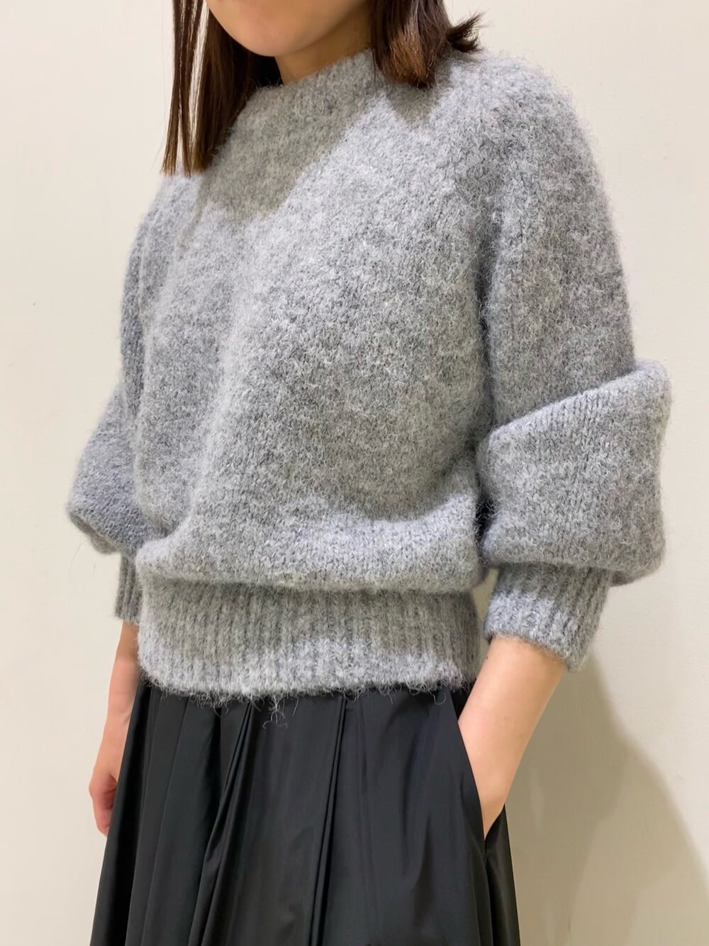 グレー系のニット/セーター、ブラック系のスカートを着用したレディースの冬コーディネートの2枚目の写真