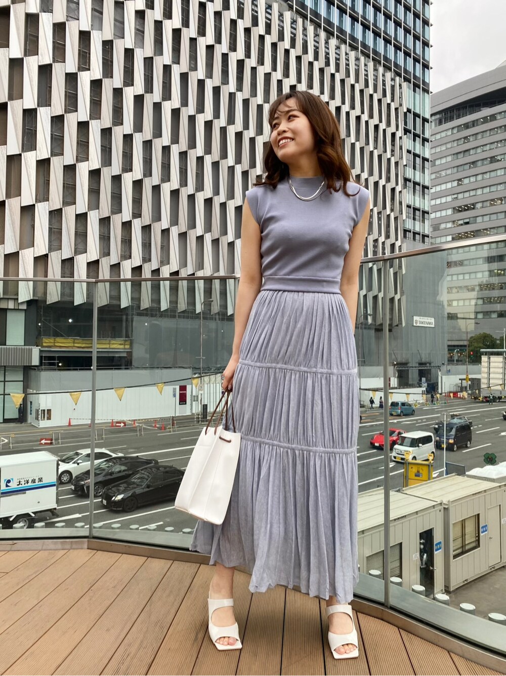 ホワイト系のサンダル、ホワイト系のハンドバッグ、ブルー系のワンピースを着用したレディースの春コーディネートの2枚目の写真