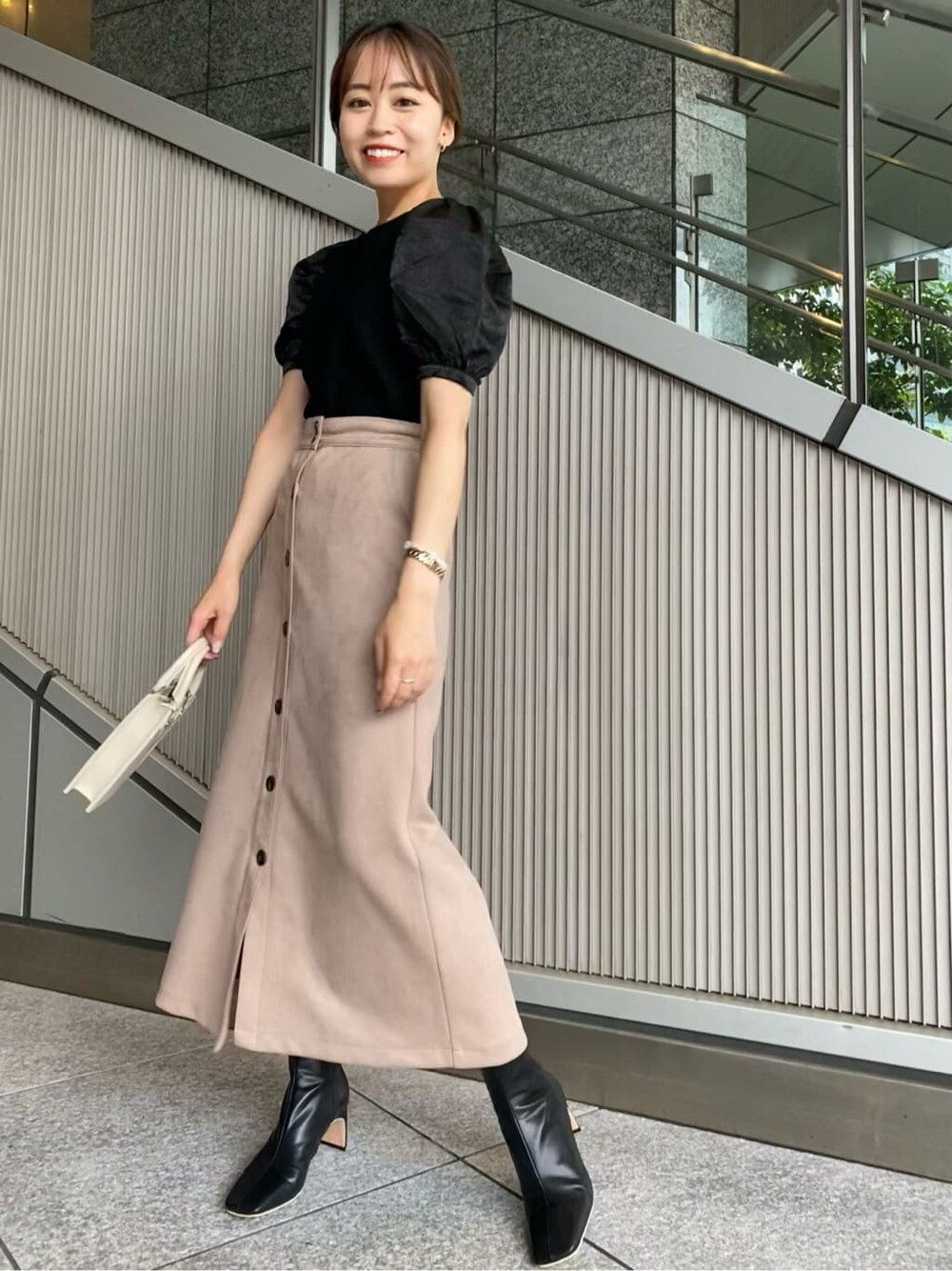 ブラック系のニット/セーター、ベージュ系のスカート、ブラック系のその他シューズを着用したレディースの夏コーディネートの4枚目の写真