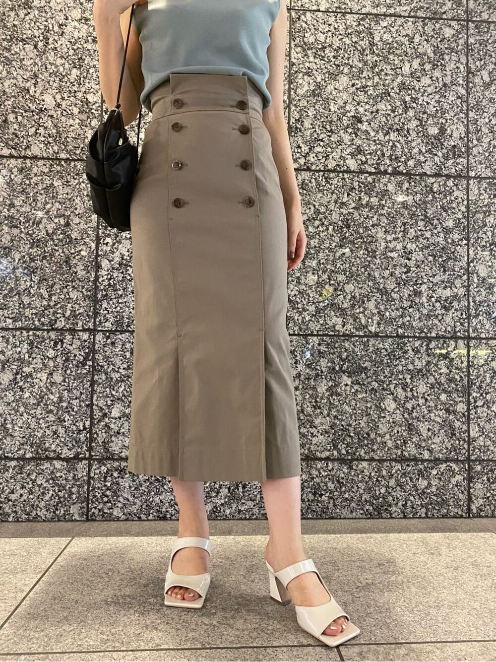 グリーン系のニット/セーター、ホワイト系のサンダル、ブラック系のハンドバッグを着用したレディースの夏コーディネートの4枚目の写真