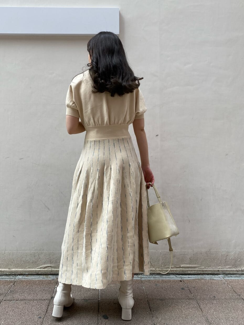 ベージュ系のトレンチコート、ホワイト系のワンピース、ホワイト系のハンドバッグを着用したレディースの春コーディネートの4枚目の写真