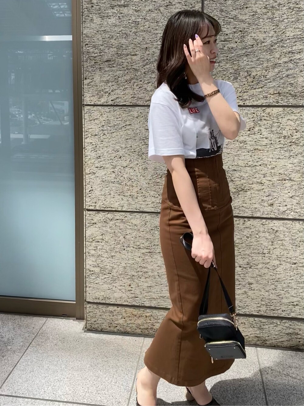 ブラウン系のスカート、ブラック系のその他シューズ、ホワイト系のTシャツ/カットソーを着用したレディースの春コーディネートの3枚目の写真