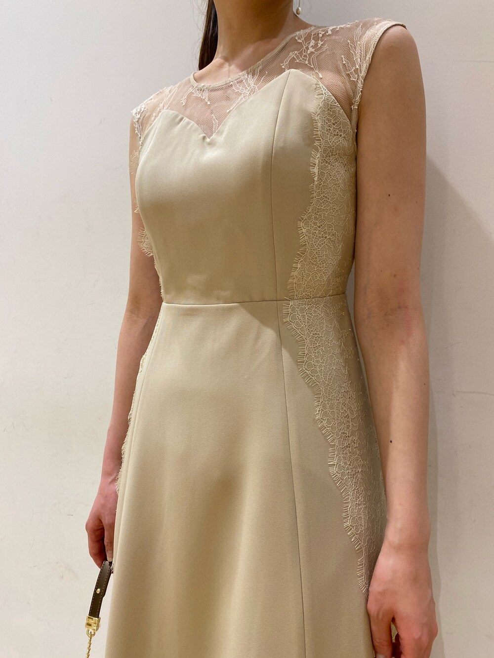 ベージュ系のドレス、ゴールド系のクラッチバッグ、ゴールド系のパンプスを着用したレディースの春コーディネートの2枚目の写真