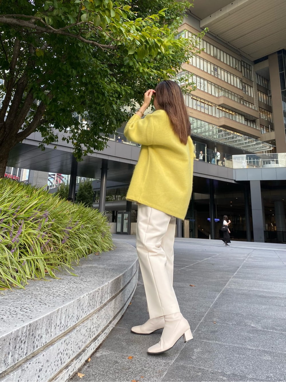 ホワイト系のステンカラーコート、ホワイト系のその他パンツ、ホワイト系のハンドバッグを着用したレディースの秋コーディネートの9枚目の写真