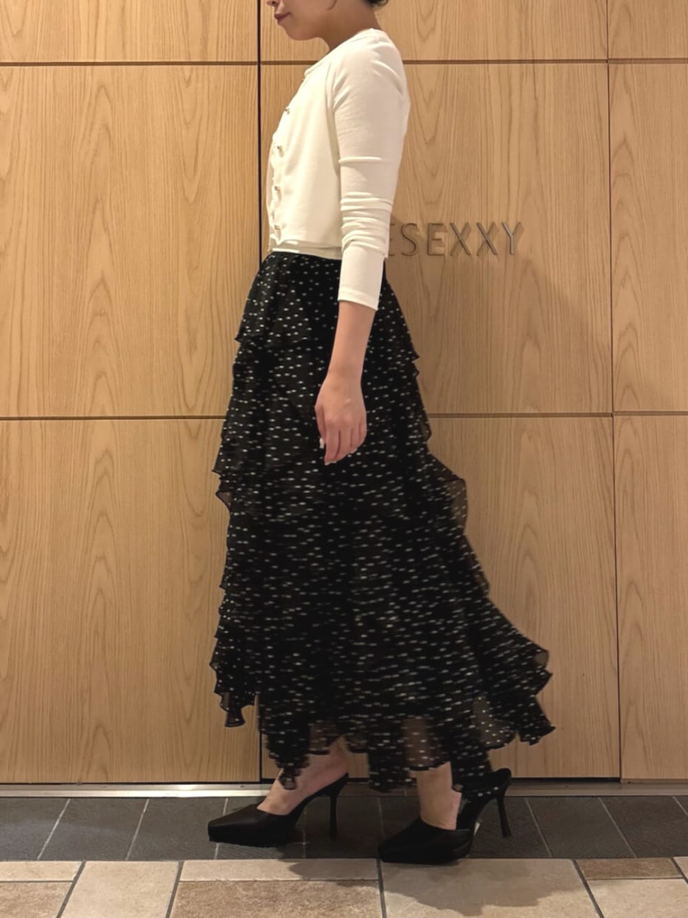 ブラック系のパンプス、ホワイト系のカーディガン/ボレロ、ホワイト系のスカートを着用したレディースの秋コーディネートの2枚目の写真