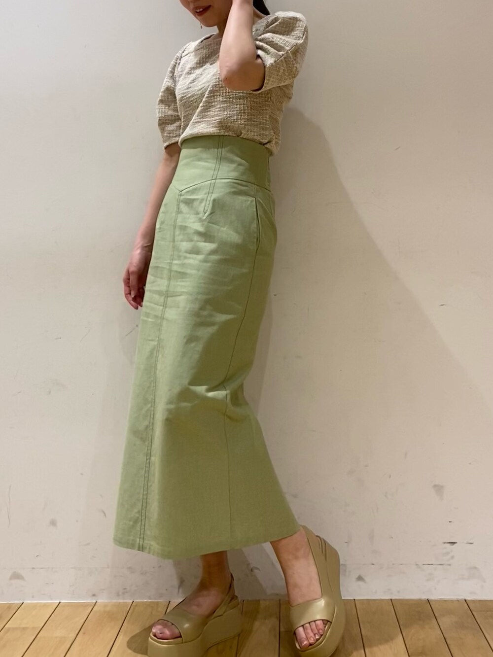 ベージュ系のTシャツ/カットソー、グリーン系のスカート、ベージュ系のサンダルを着用したレディースの春コーディネートの3枚目の写真