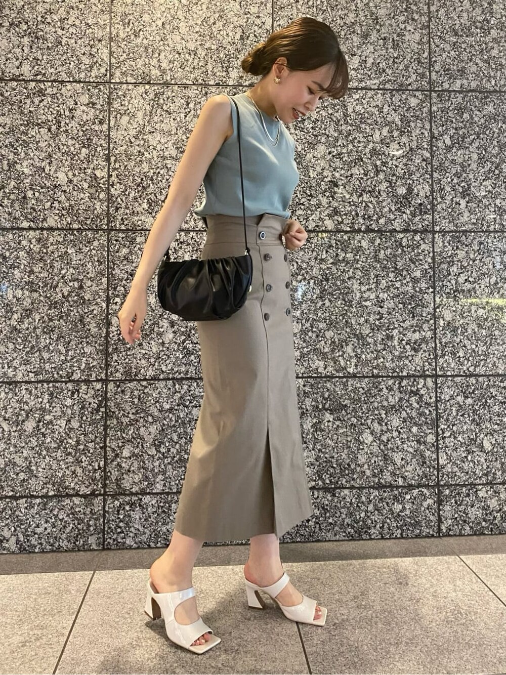 グリーン系のニット/セーター、ホワイト系のサンダル、ブラック系のハンドバッグを着用したレディースの夏コーディネートの2枚目の写真