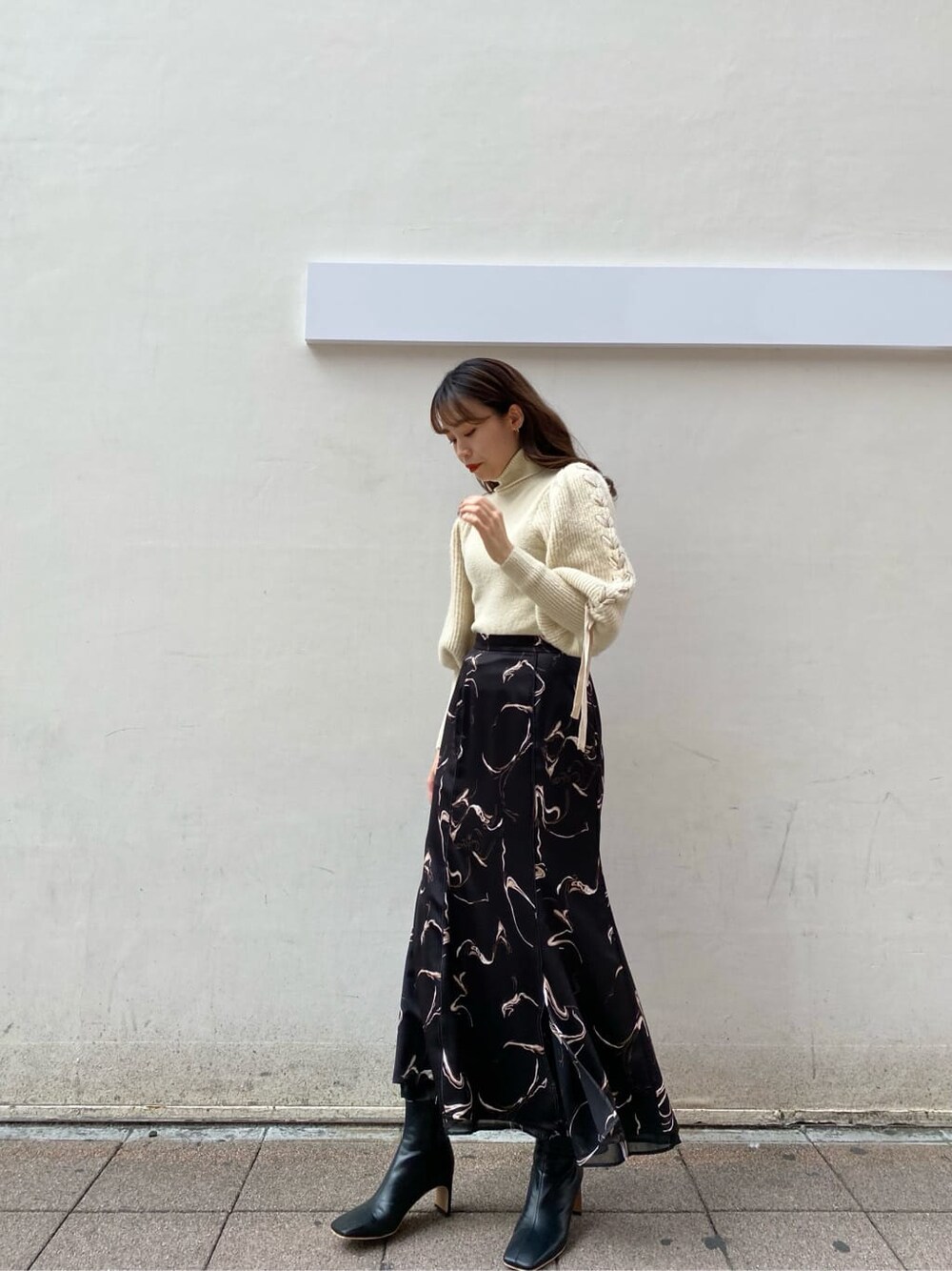ブラック系のスカート、ホワイト系のニット/セーターを着用したレディースの秋コーディネートの4枚目の写真