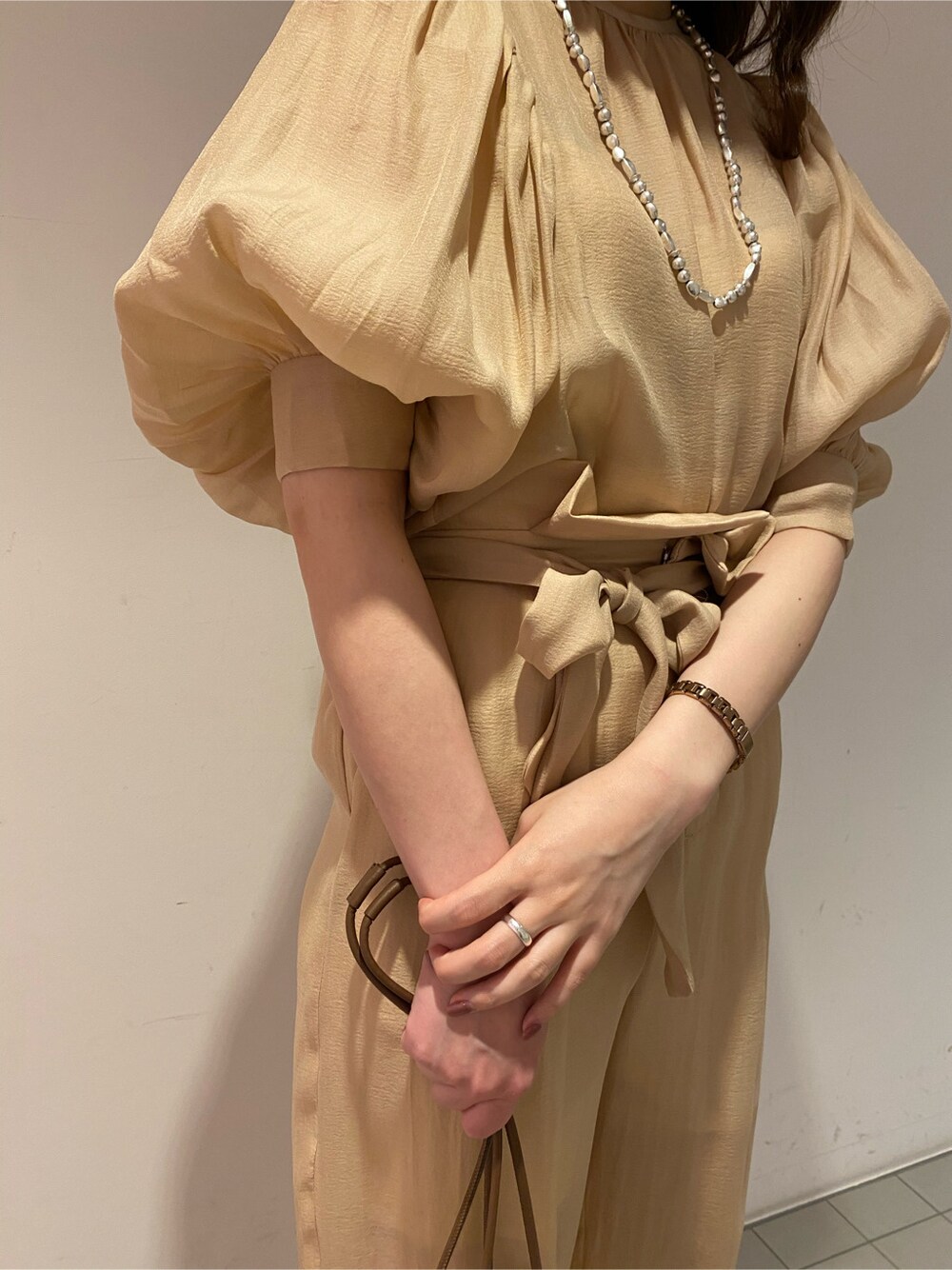 ブラウン系のパンプス、ホワイト系のハンドバッグ、ベージュ系のシャツ/ブラウスを着用したレディースの春コーディネートの2枚目の写真